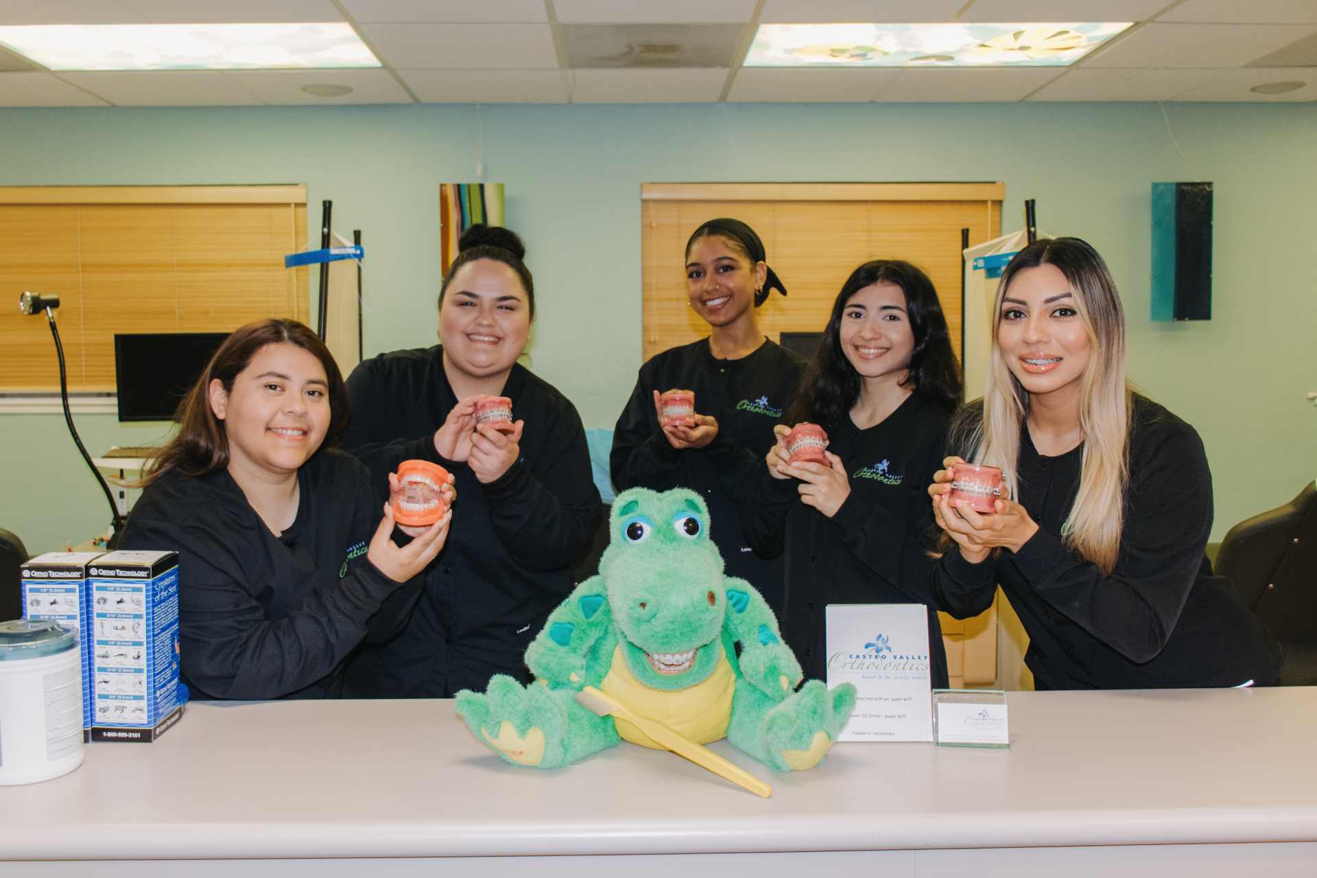 Five team members holding teeth models and posing with alligator toy.