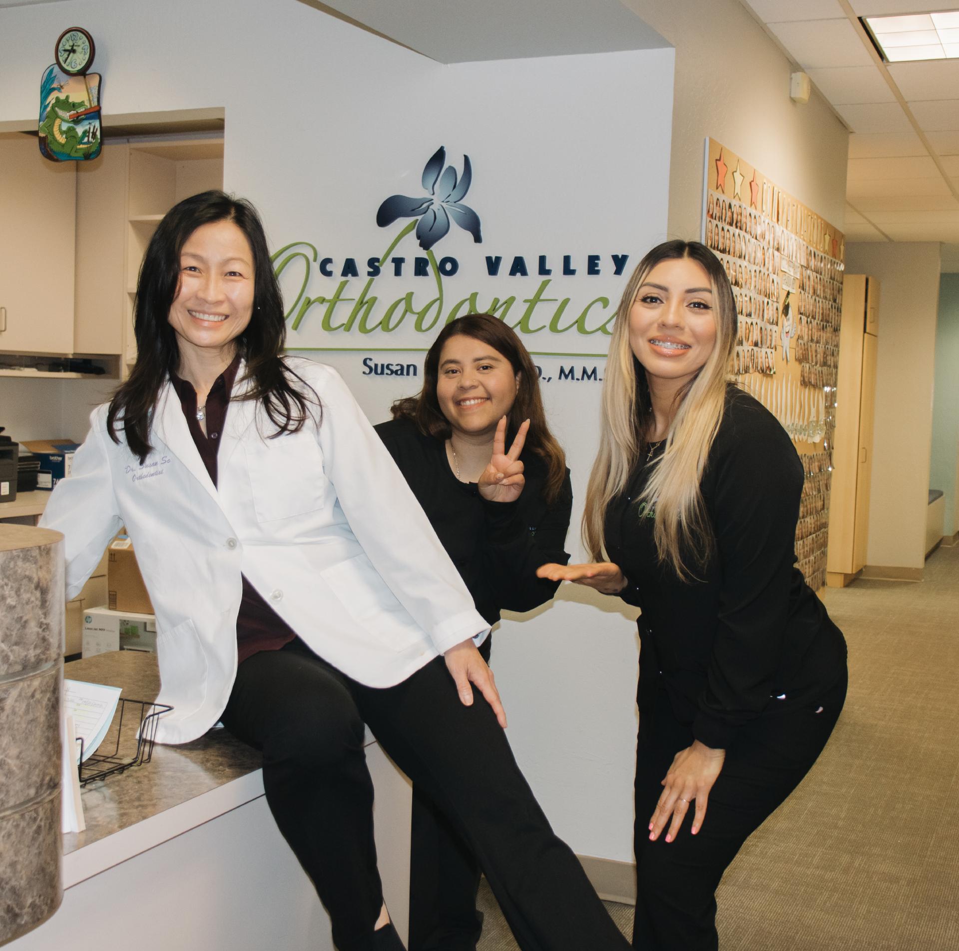 Three team members smiling and posing at the front desk