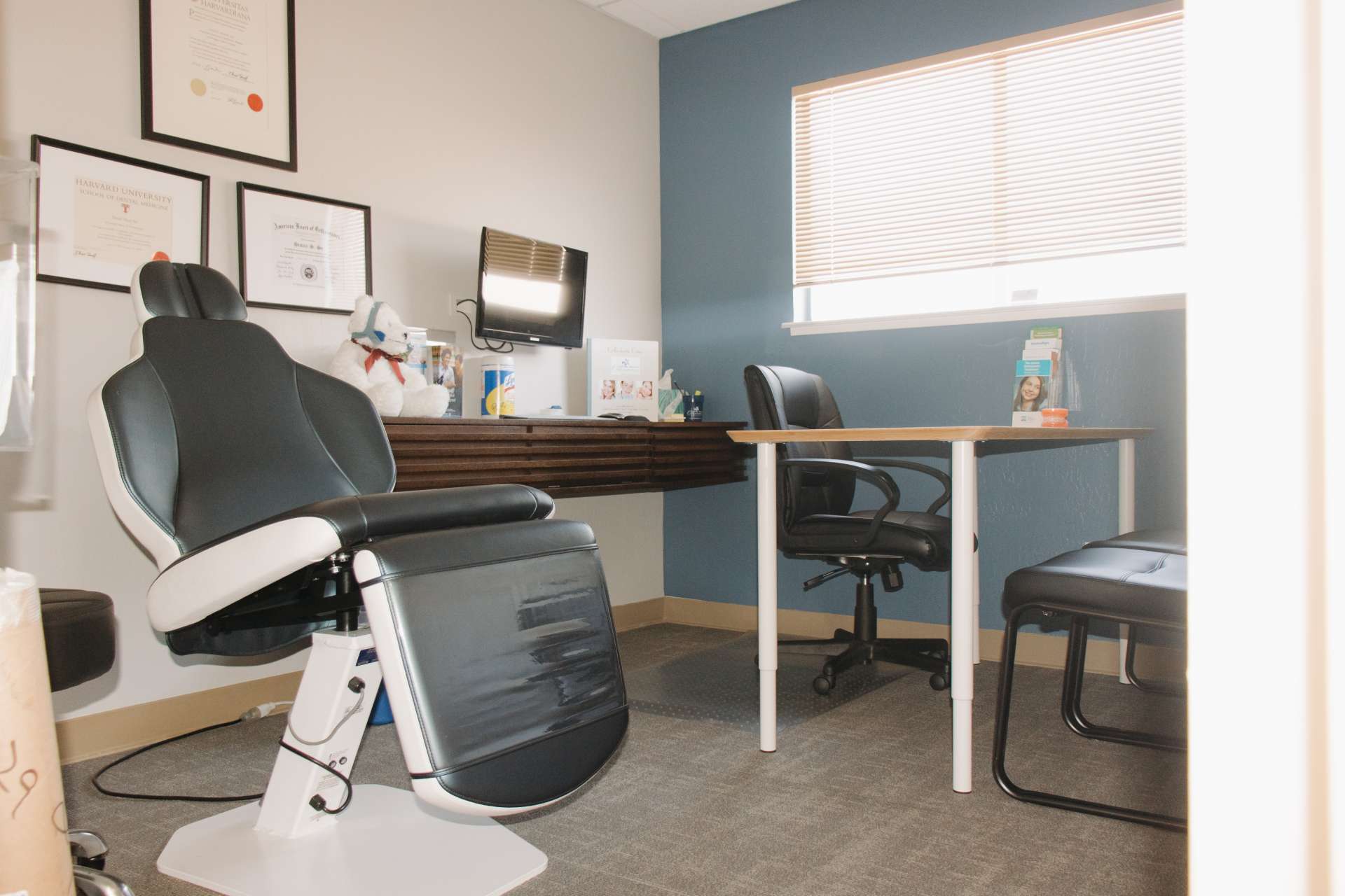 Exam room with exam chair, desk, and seating area